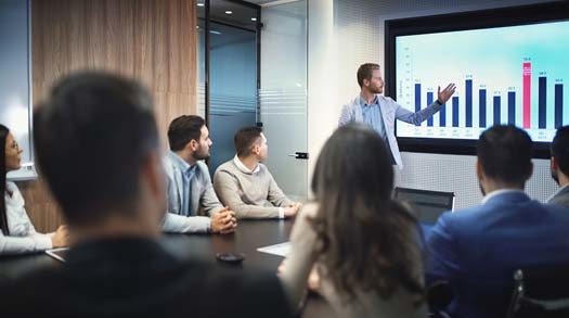 employees in a boardroom meeting viewing a graphic chart of growth